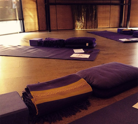 Yoga mats, blankets, and cushions spread out around a yoga studio.